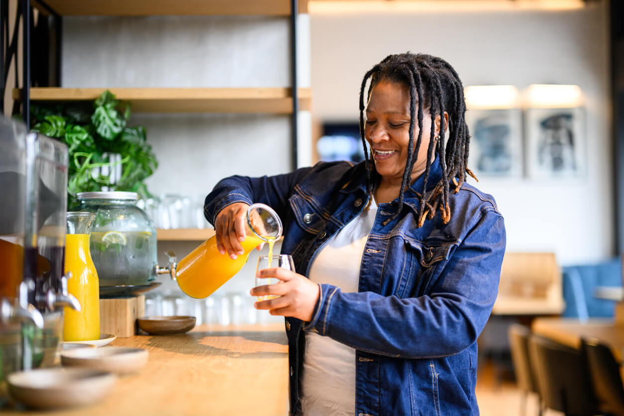  Young woman pouring a juice at a self-serve hotel breakfast bar. 