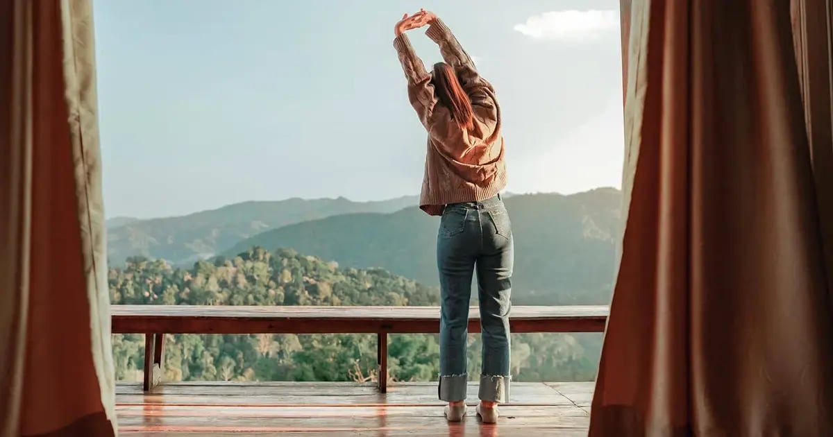 Photo of a young woman stretching and enjoying the view on the deck of a sustainable hotel property.