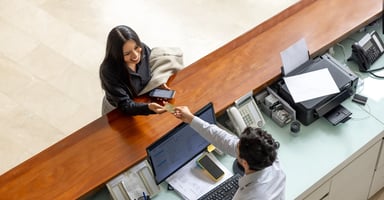 Photo of guest and front desk staff member conversing as the guest makes a payment.