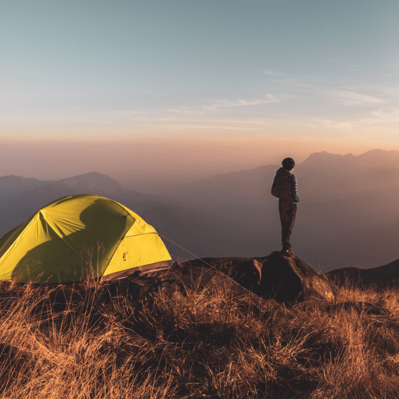 Man on top of a mountain, next to a tent