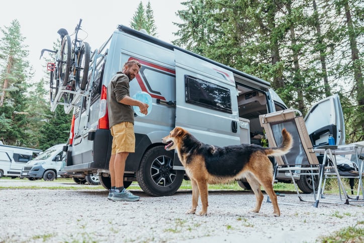 Man Camping with Dog Near Camper Van Outdoors