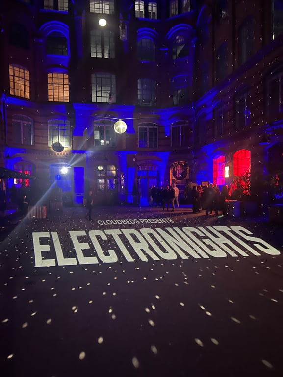 Picture of a night club with a disco ball and the word electronights projected on the floor