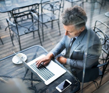 Man in suit using laptop at cafe