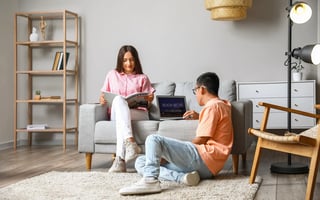 Photo of a couple relaxing as the man looks into booking a hotel room online.