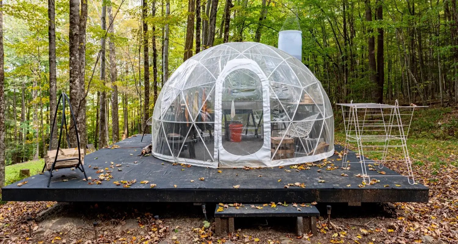 Photo of a geodesic dome on a wooden platform near woodlands, showing how eco-friendly structures can be used for outdoor accommodation.