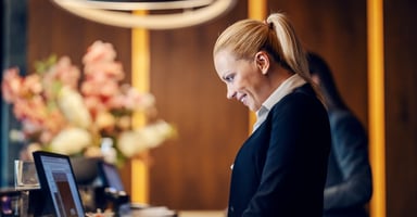 A hotel receptionist engrossed in her work as she makes an online reservation on a PC.