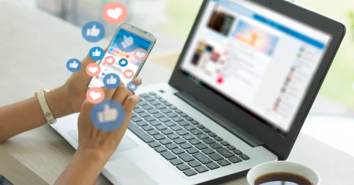 Marketing manager at laptop while using a smart phone to monitor social media. Thought bubbles showing engagement.