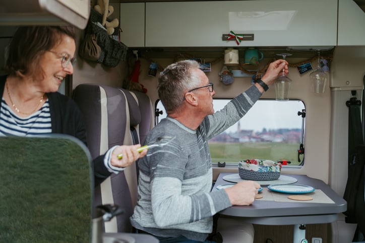 Two people in a campervan sitting down and setting the table