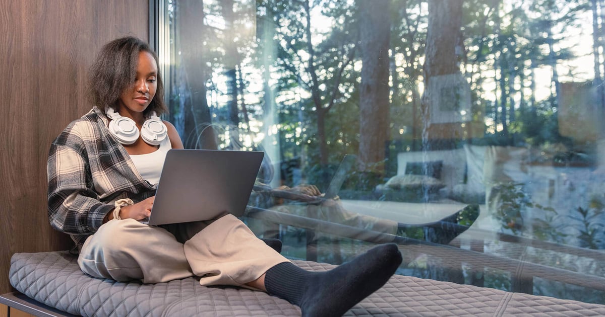Photo of a young woman working on a laptop PC while enjoying a glamping holiday.
