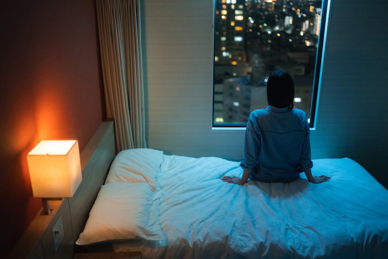 Woman sitting on a bed alone at night