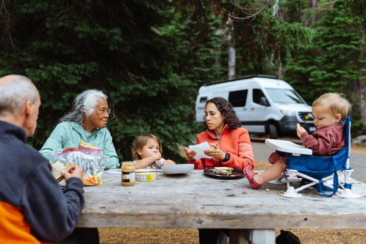 A family group enjoying a meal beside their motor home
