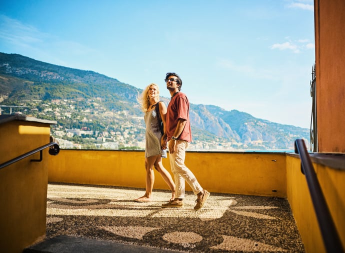 A couple walking hand in hand on a sunny terrace