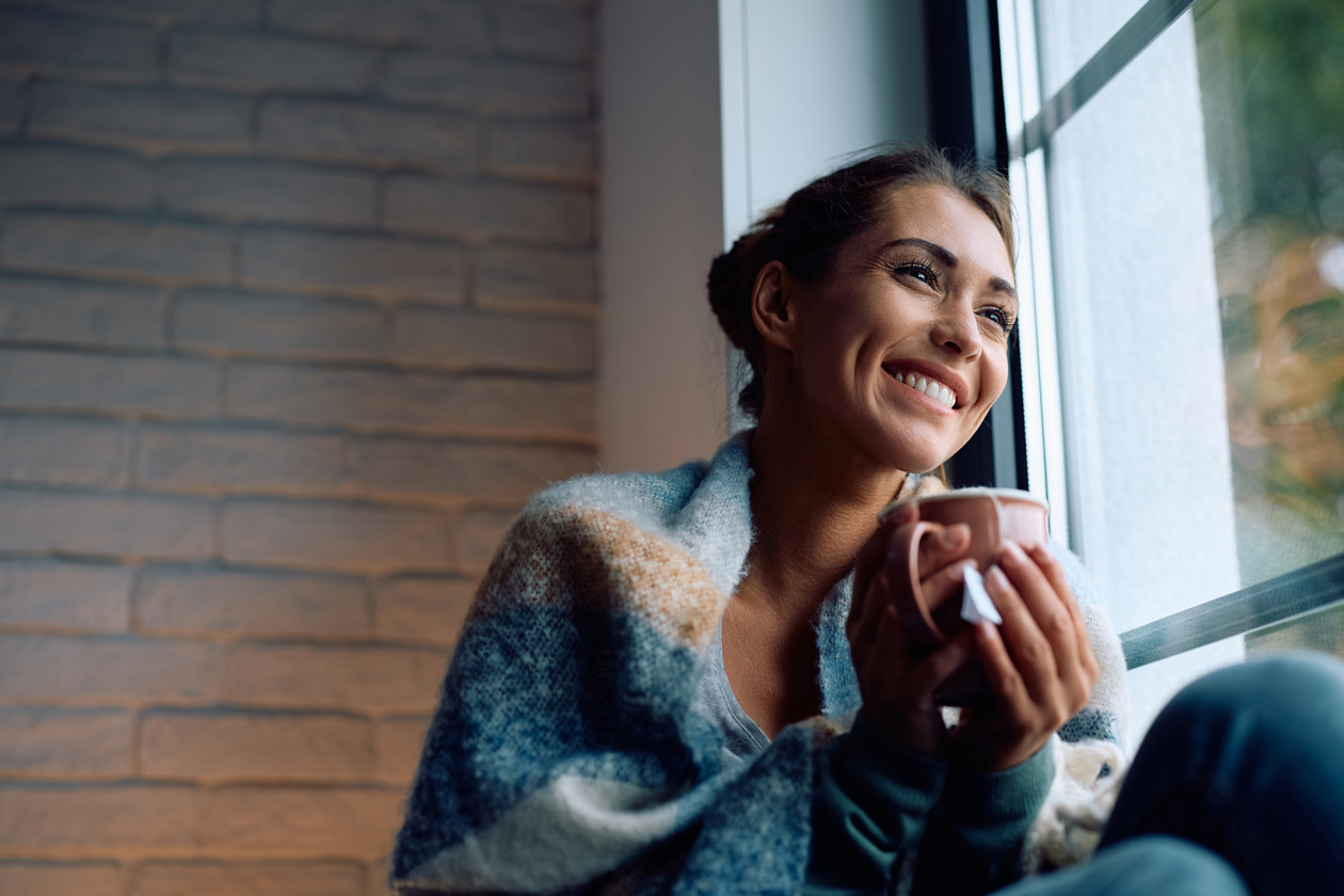 Woman holding a cup of coffee leaning on a window