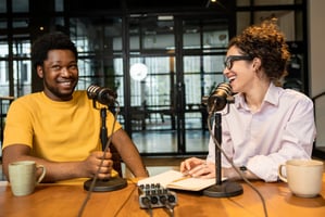 Photo of people making a podcast with one person recording an interview with the other.