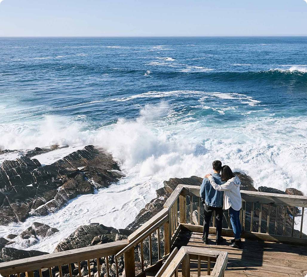 Couple watching waves crashing on rocks