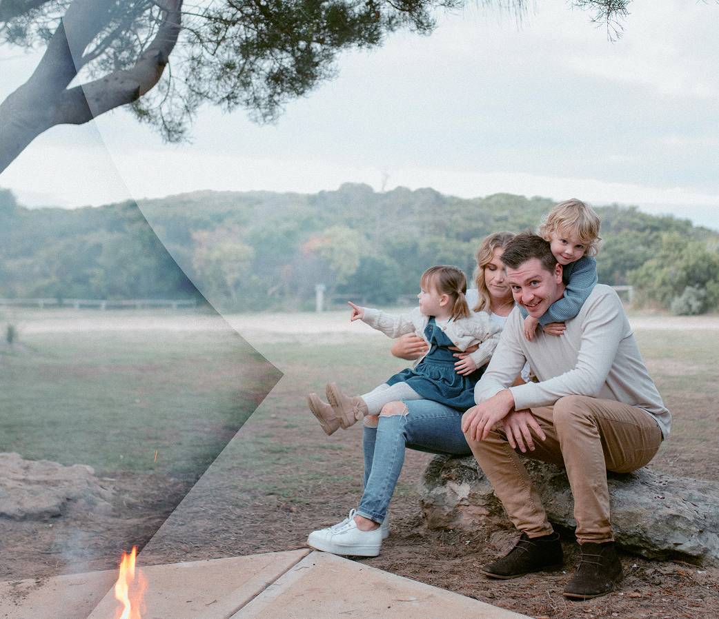 Family sat on log with fire pit
