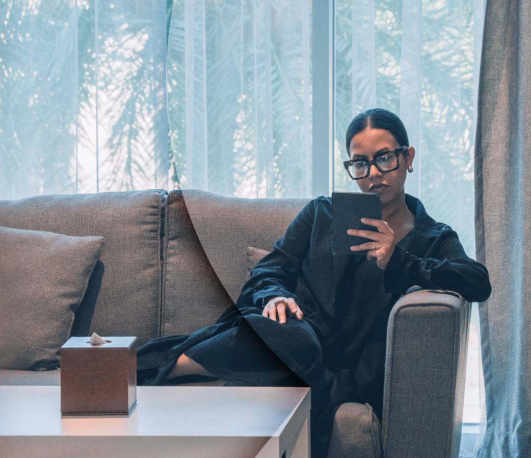 Woman sitting on sofa holding tablet