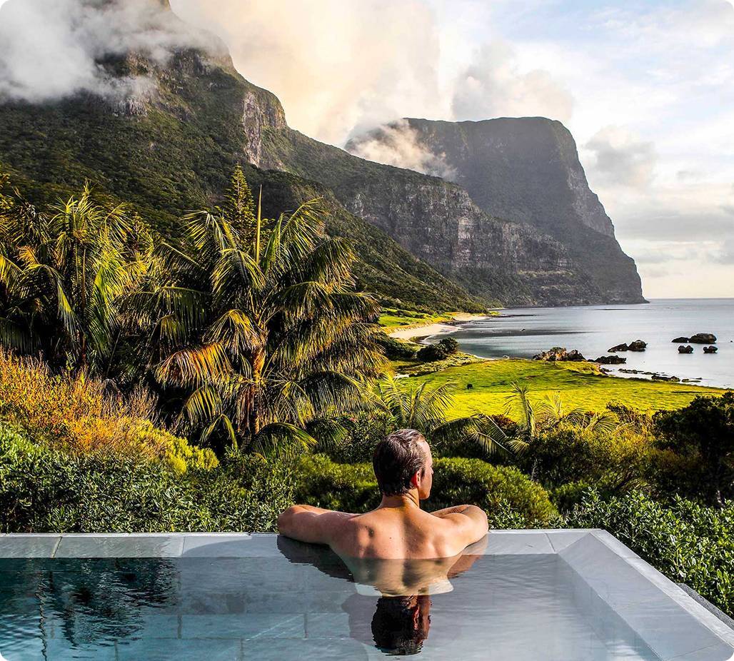 Man in hot tub looking out at island coast