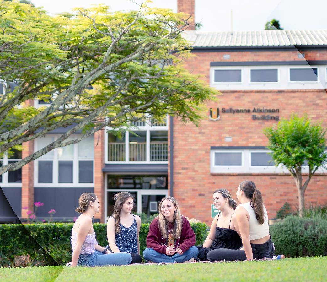 Group of students sitting on grass outside accommodation building